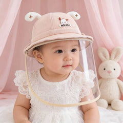 Baby wearing pink face shield hat with white dress