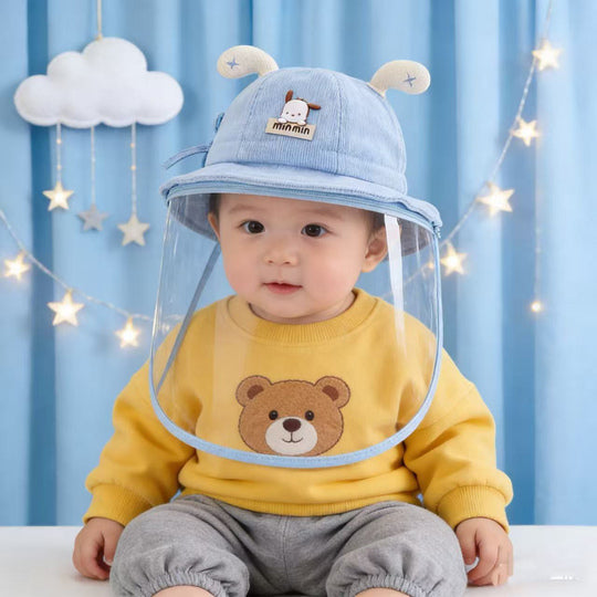Baby wearing blue face shield hat with yellow top