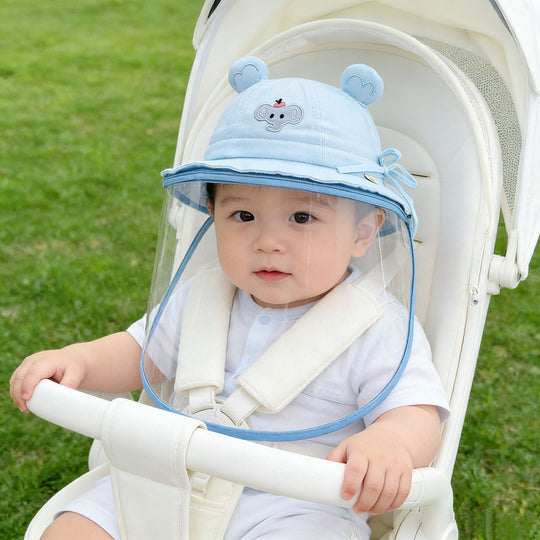 Baby wearing blue elephant-detail face shield hat in stroller